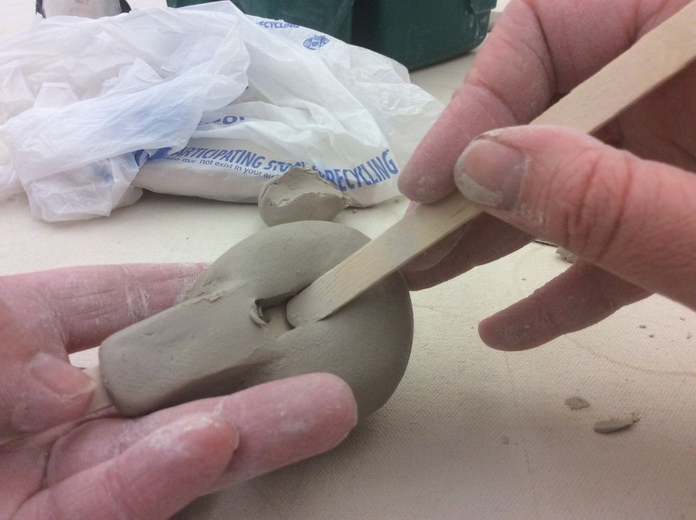 Using a Popsicle stick, push the farthest end of the opening down to a 45 degree angle to the first Popsicle stick.