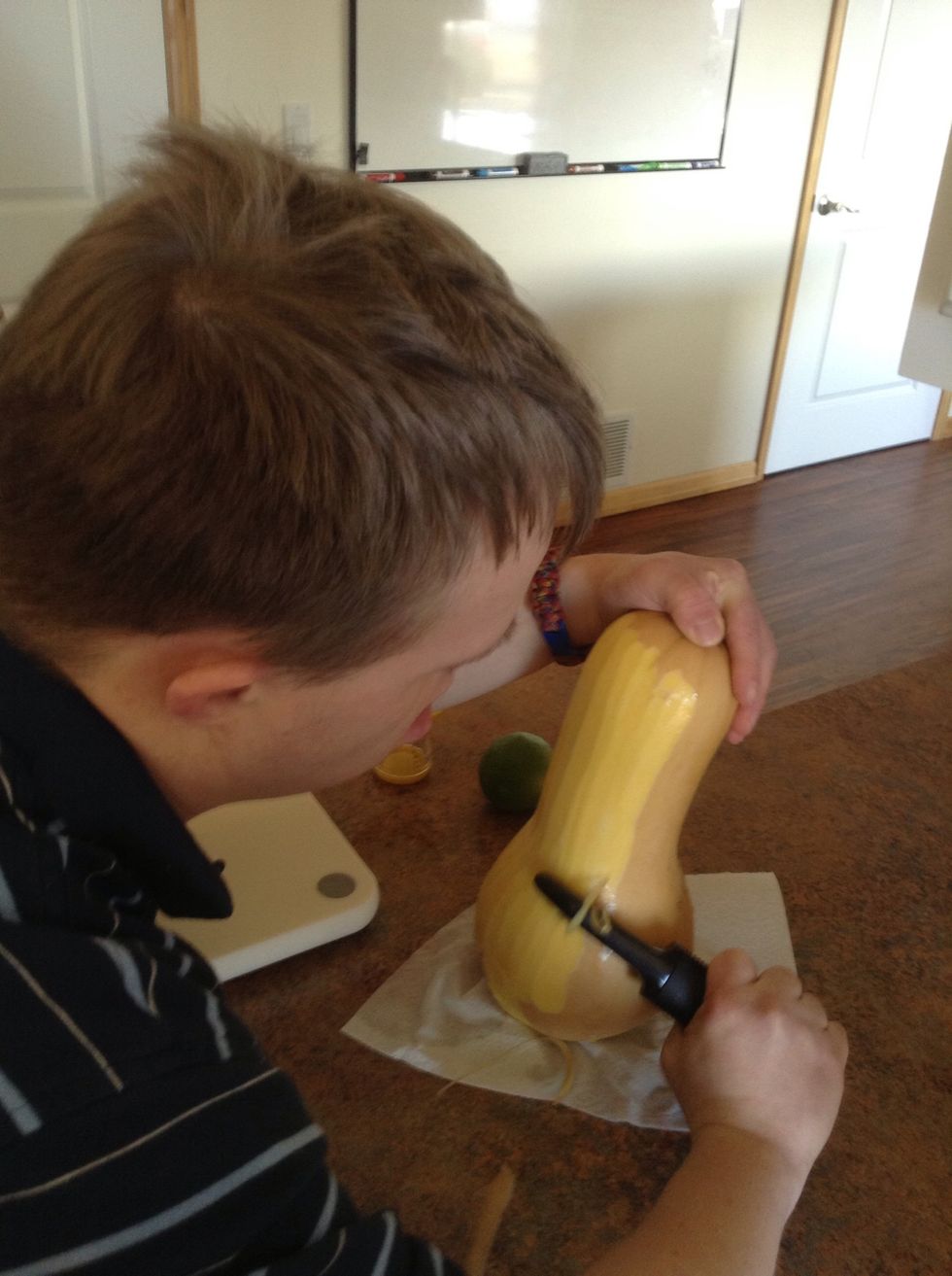 Using a potato peeler peel skin off butternut squash