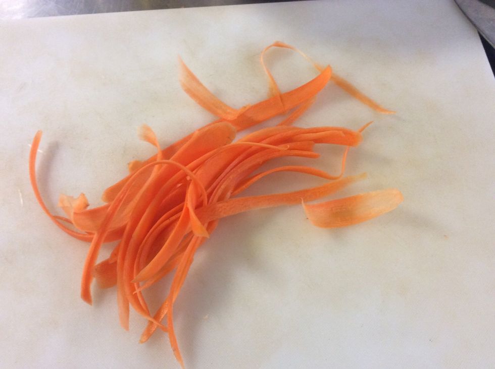 Using a potato peeler, peel the carrot into fine stripes then slice into batons.
