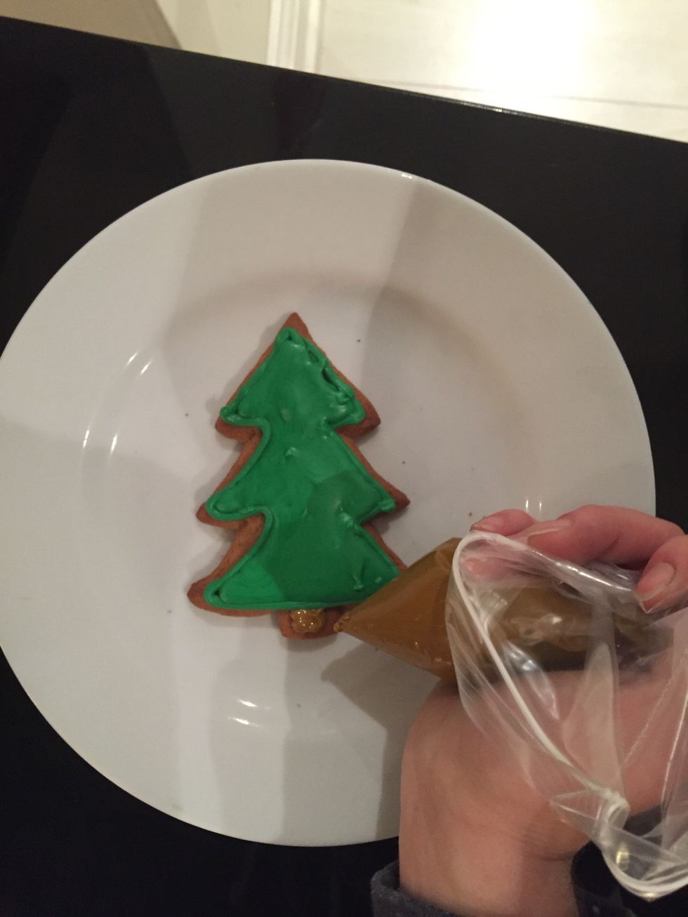 Using a quarter of the remaining icing, colour it brown and pipe it on as the base of the tree.