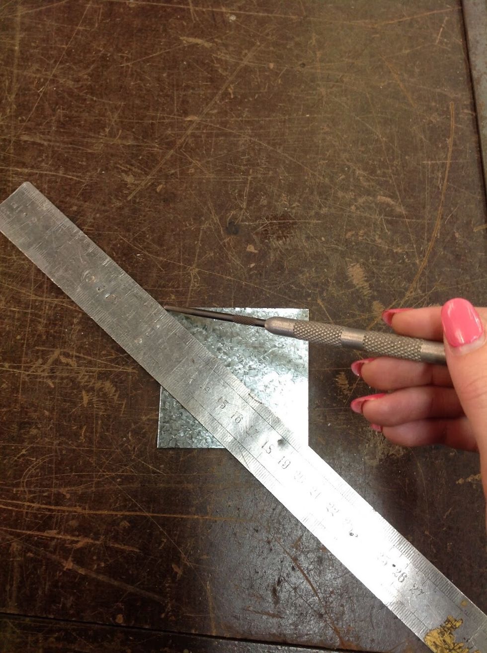 Using a ruler and scribe, mark out a cross from corner to corner.