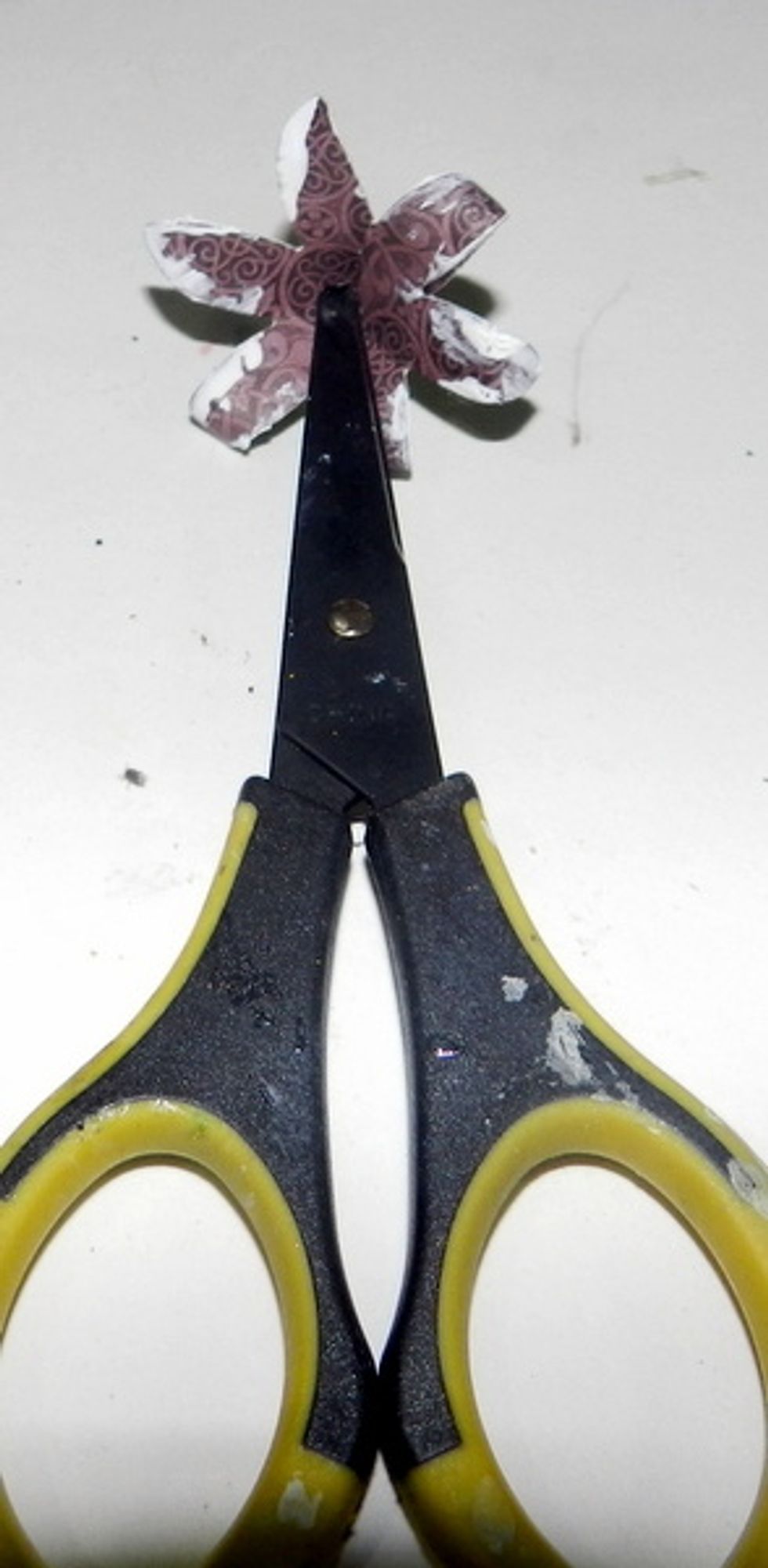 Using a scissor, you must make a hole in the center of the flower.