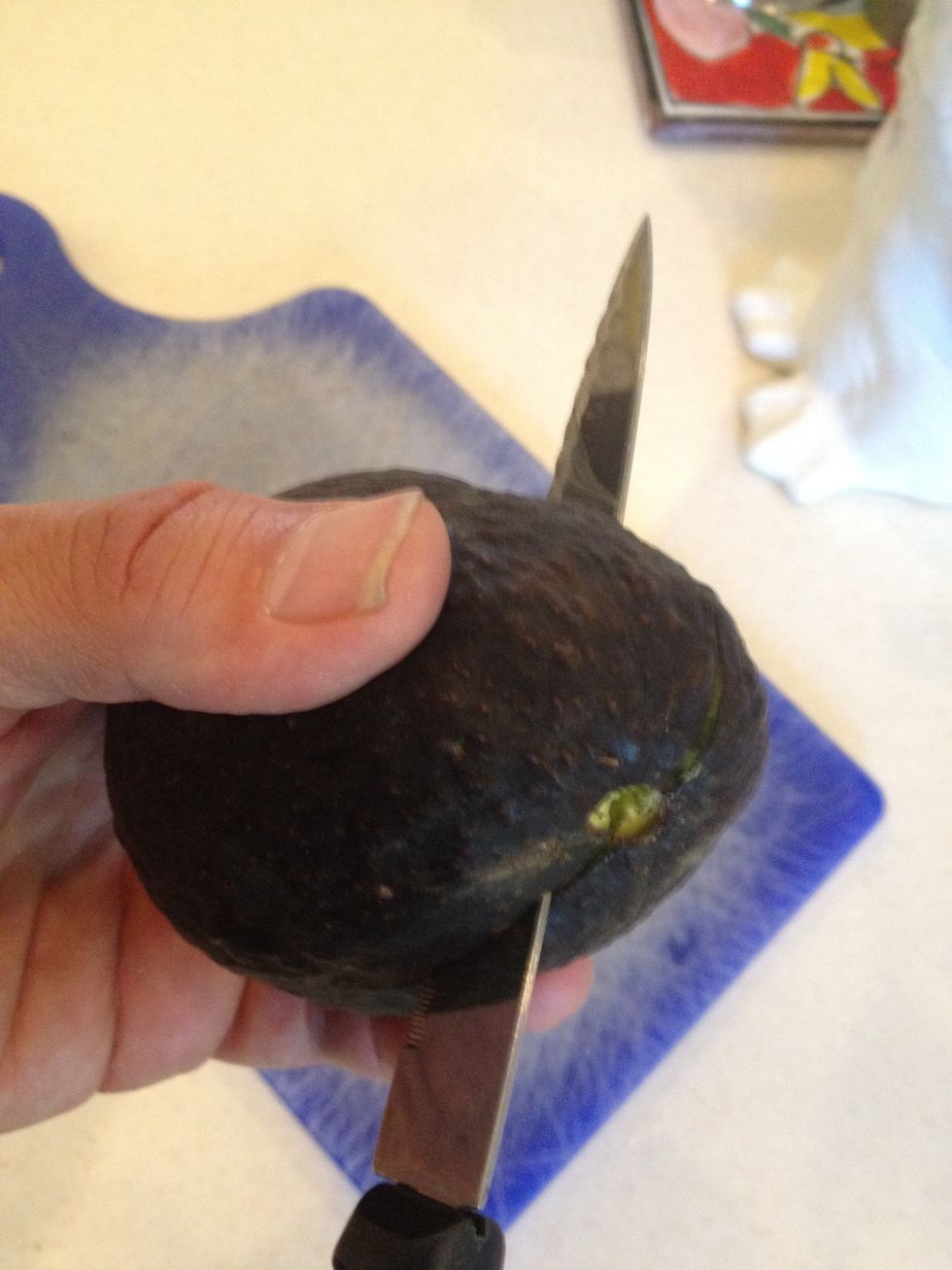 Using a sharp knife, cut through avocado's skin and meat, stopping at the pit. Revolve the avocado on the blade until the fruit is cut in half on the pit.