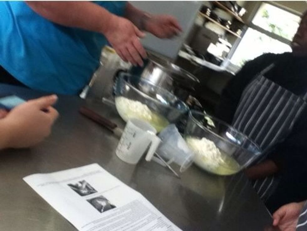 Using a slotted spoon to scoop the curds out. Split into to two bowls to began the draining and kneading stage.