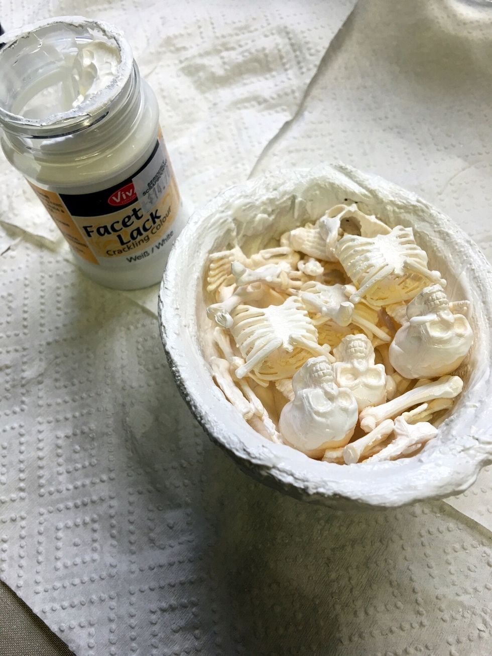 Using a small paint brush apply crackle medium to the outside of the egg, the rim of the egg and random parts of the plastic skeletons. Allow to dry.