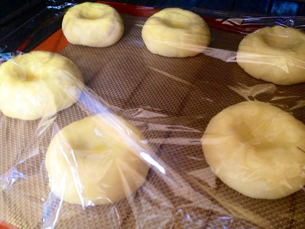 Using a small spoon, slightly flatten the middle of the dough. Brush each piece with the egg glaze. Cover the pieces with Saran Wrap.