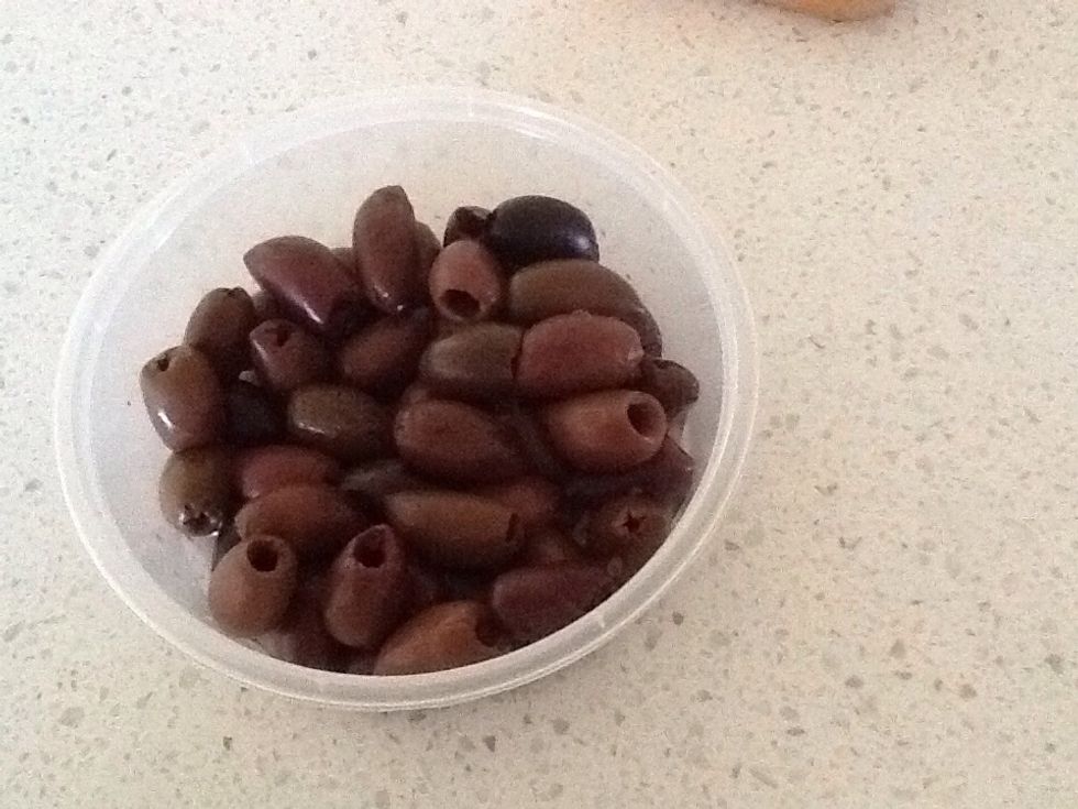 Using a spoon, pick up the olives and place them in the dish you have set out for this Greek Salad