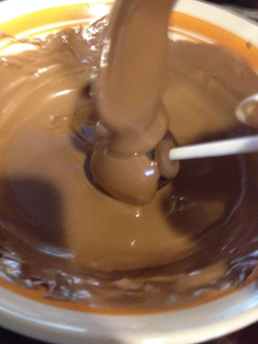 Using a spoon, pour chocolate all over the cake pop. Be careful to not pour too much or else the cake will fall off the stick