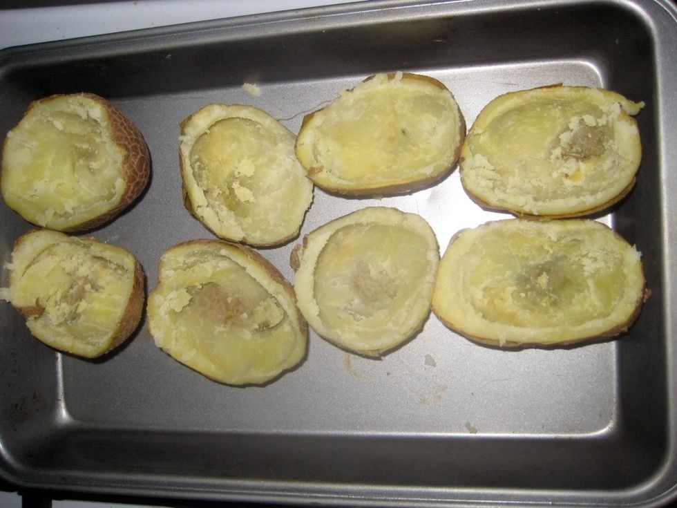 Using a spoon, scoop out the potato leaving the skin intact