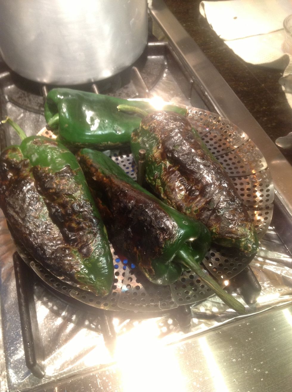 Using a steel vegetable steamer directly on gas burner roast poblano chilies blackening skin thoroughly. Place in brown paper bag for about 5 minutes before peeling. You can also broil them in oven.