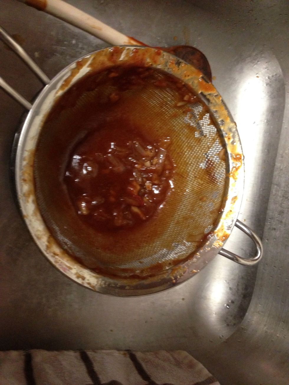 Using a strainer, pour the sauce into another bowl to remove the onion and garlic solids. You may want to repeat this process two or three times to make sure you remove them all.
