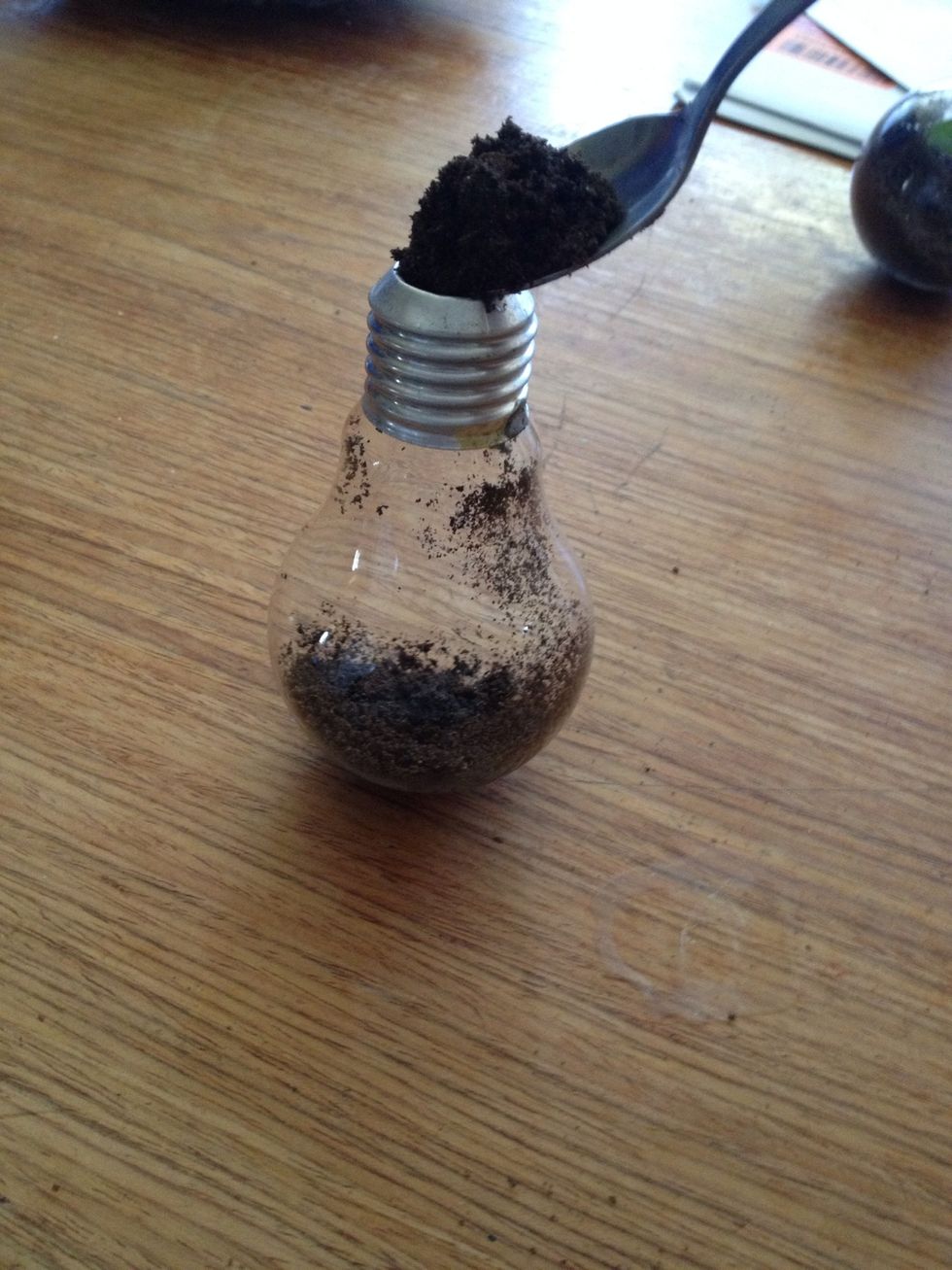 Using a teaspoon simply fill it up with soil/sand a little less than half way.