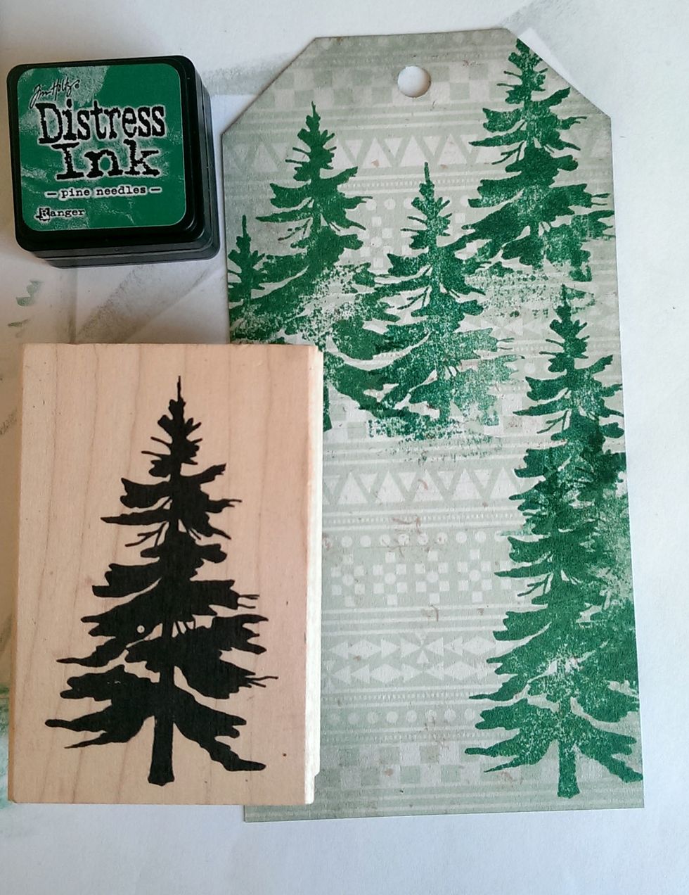 Using a Tree Stamp and the Pine Needles Distress Ink, stamp a few random trees around the tag.