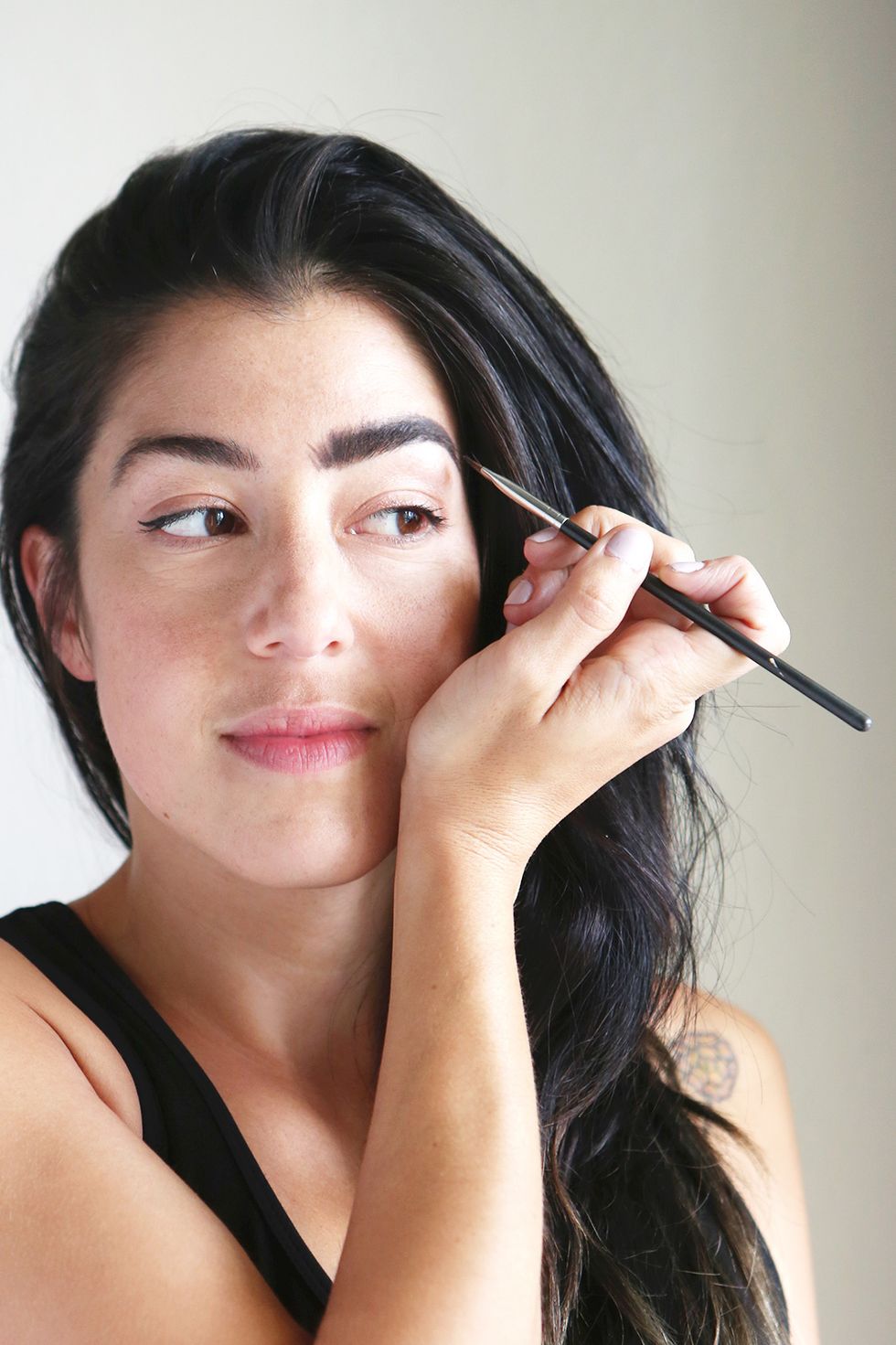 Using an angled brush, fill in your brows with a dark brown mousse. (We used Tarte EmphasEYES.) Be sure to blend using upward brushstrokes to create fullness.