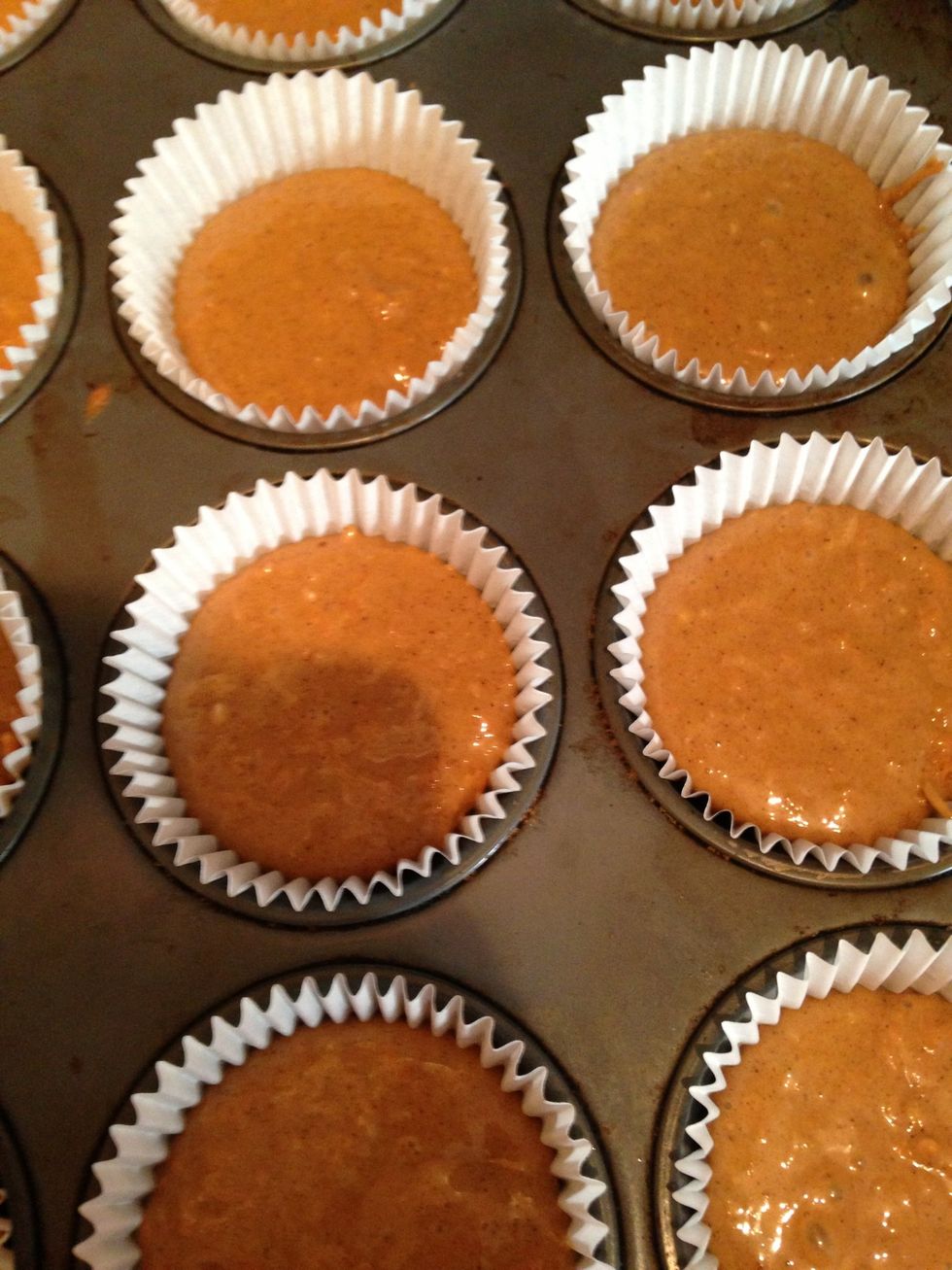 Using an ice cream scoop line a muffin tin with cupcake cases 2/3 full