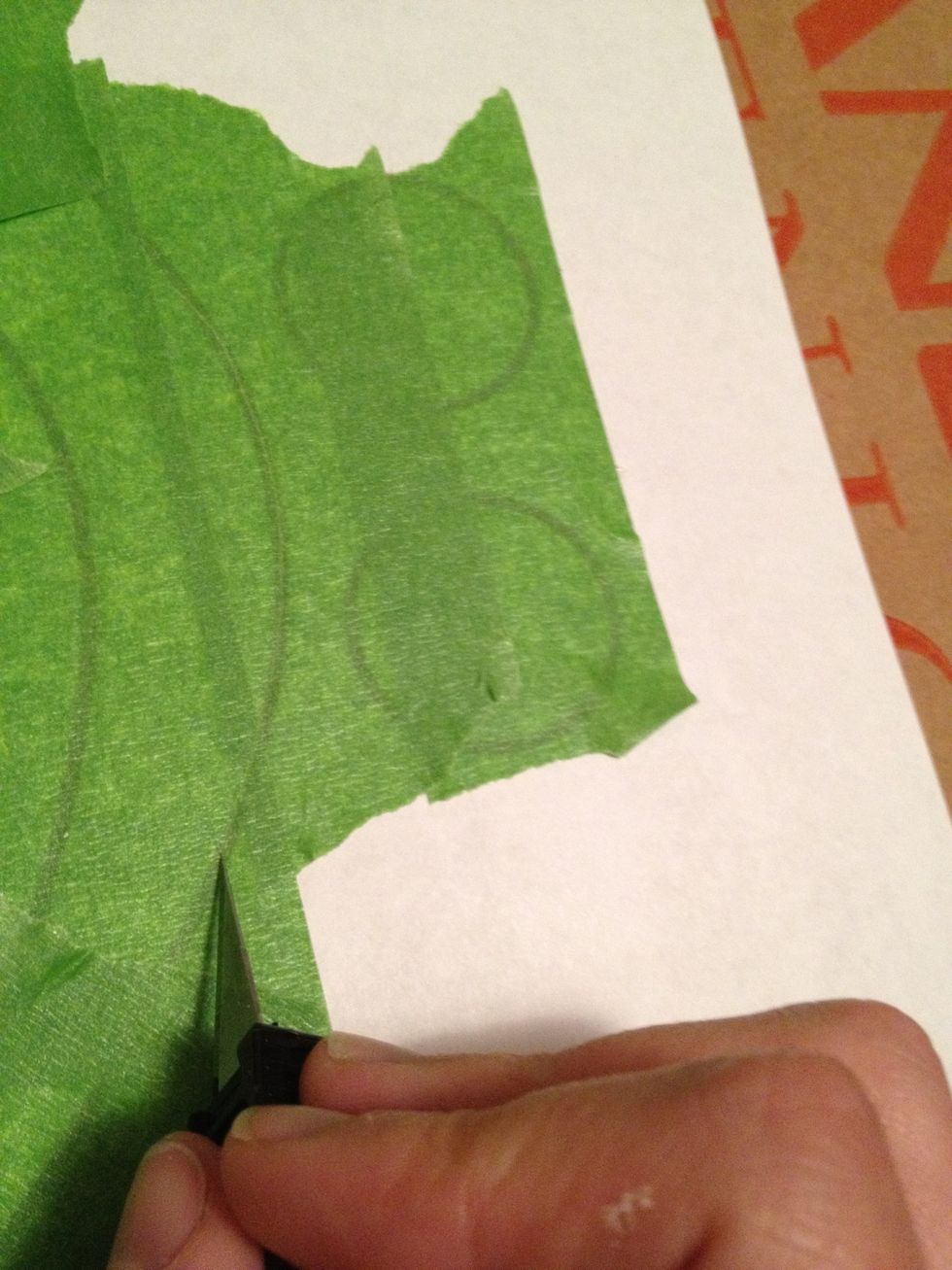 Using an x-acto knife or hobby knife on cardboard, cut the painters tape in the pattern of the stencil.