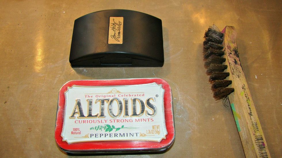 Using any kind of sanding device, rough up your mint tin to prepare for altering.