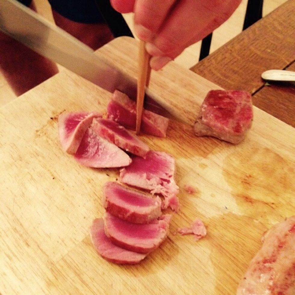 Using chopsticks to hold the tuna without spoiling the piece, slice it up quickly with a sharp knife, be careful as it's very tender.