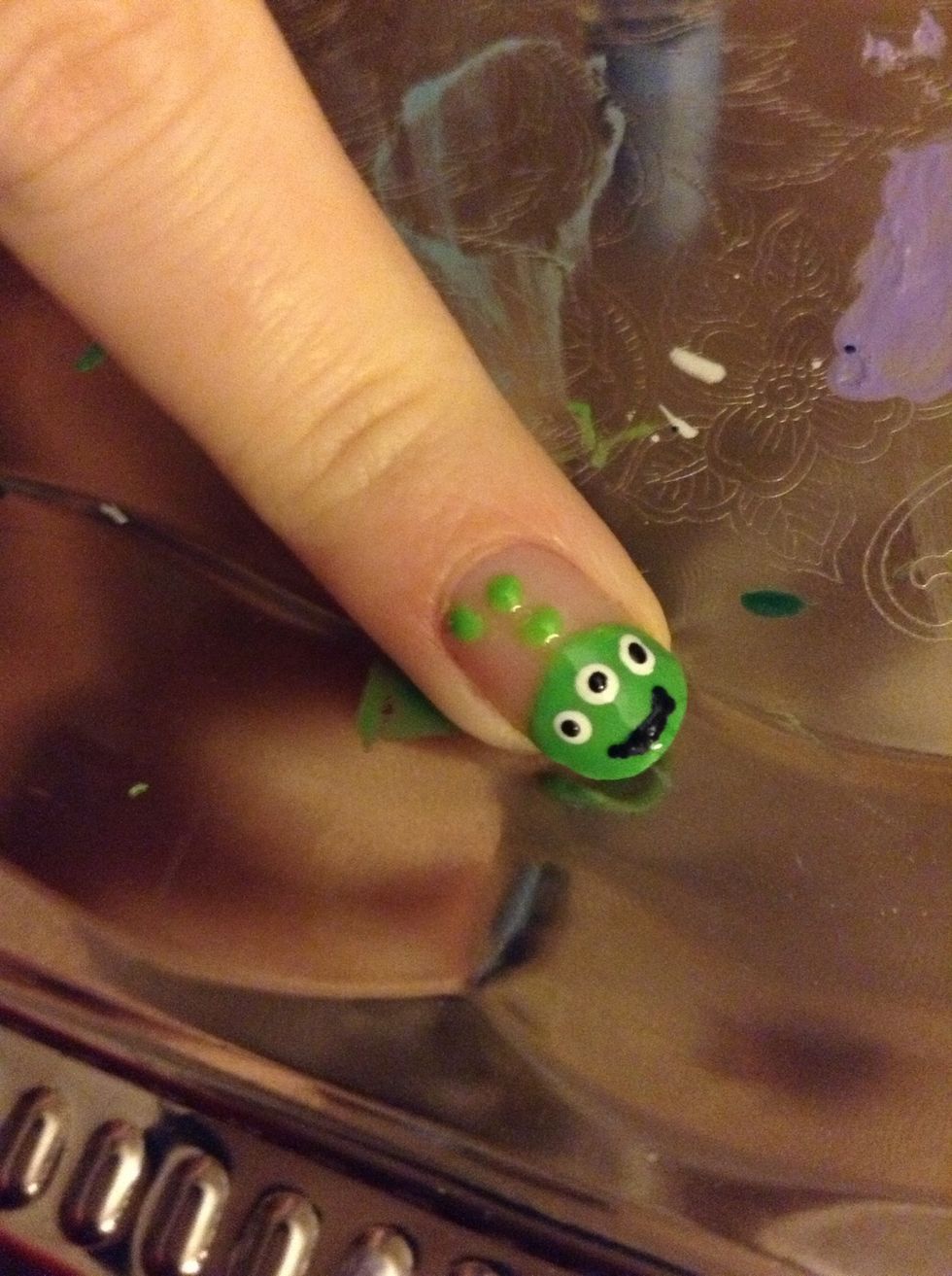 Using either a black stripped or the small end of the dotting tool (or toothpick) add a smile to the alien's face.