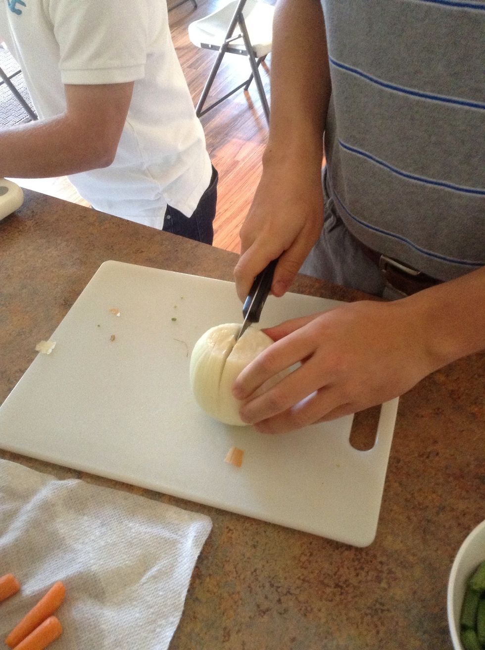 Using knife and cutting board cut the onion into slices.