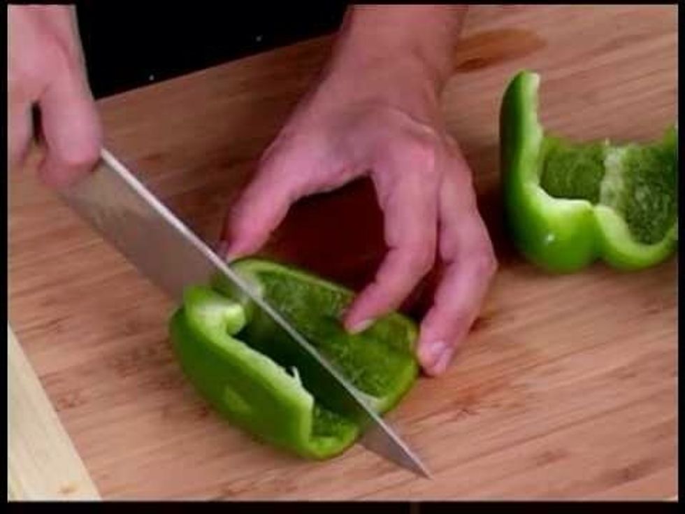 Using knife and cutting board cut the top off the green pepper.  Then slice it into 4 slices