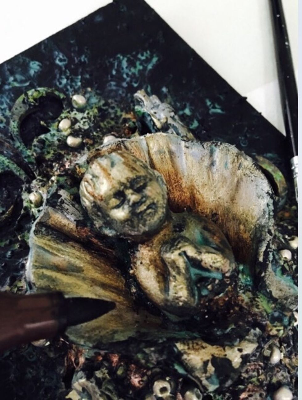 Using Marker add some warm shading in the shell coming in an outward direction from under the child. These darker areas help to create more of a glow. Also light hit the raised areas with Black Gesso