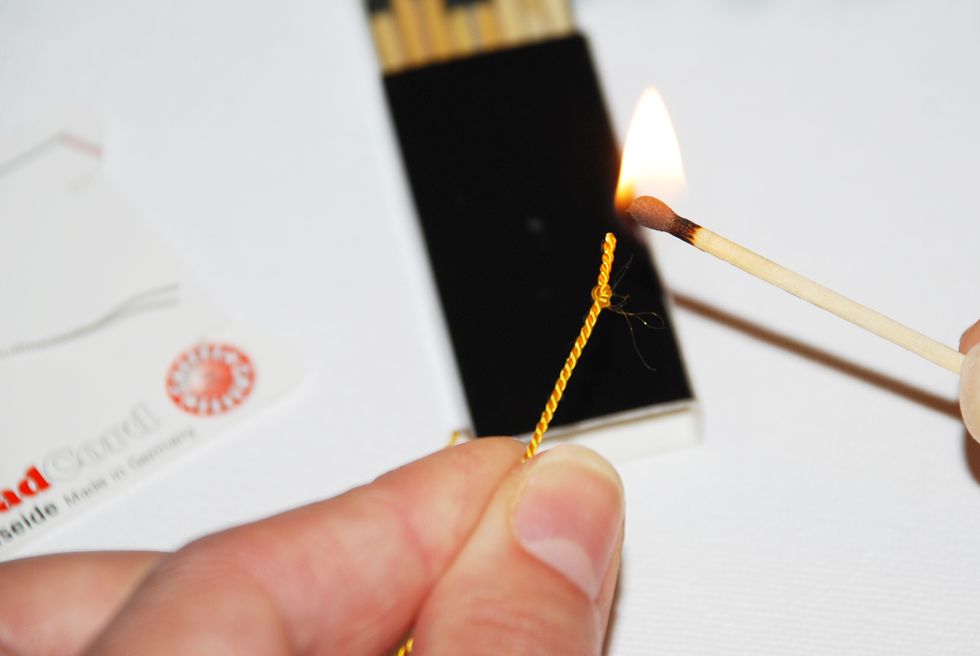 Using matches or a thread zapper, gently burn/cure the end of the thread to seal it and prevent it from fraying.