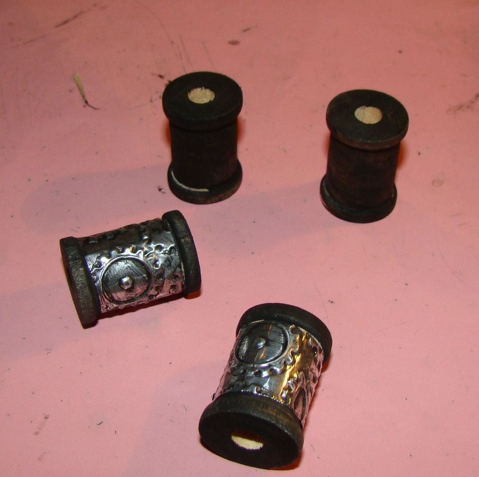 Using mini wooden spools, I painted them black, let dry, then applied strips of the metal tape around the body and painted with black for distressing.