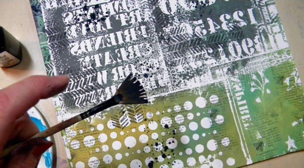 Using my fan brush, I splatter the black mixture randomly on all of the pattered cardstock.