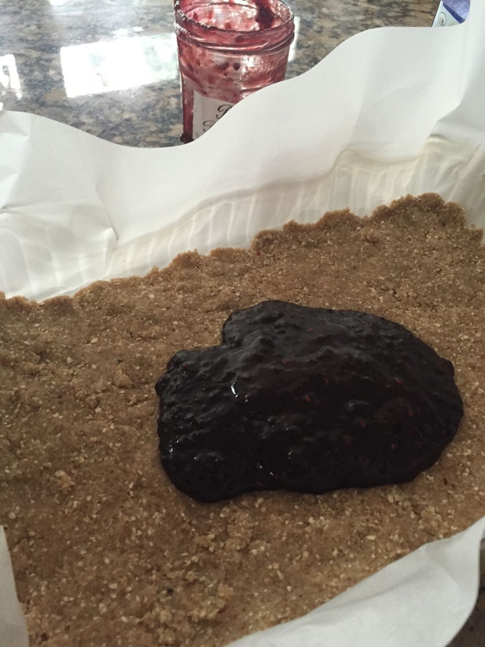 Using ONLY half of flour mixture, Press into a parchment paper lined 9x13 dish. Using the parchment makes it easier to remove once baked. Now for the jelly; I used the whole jar of raspberry preserves