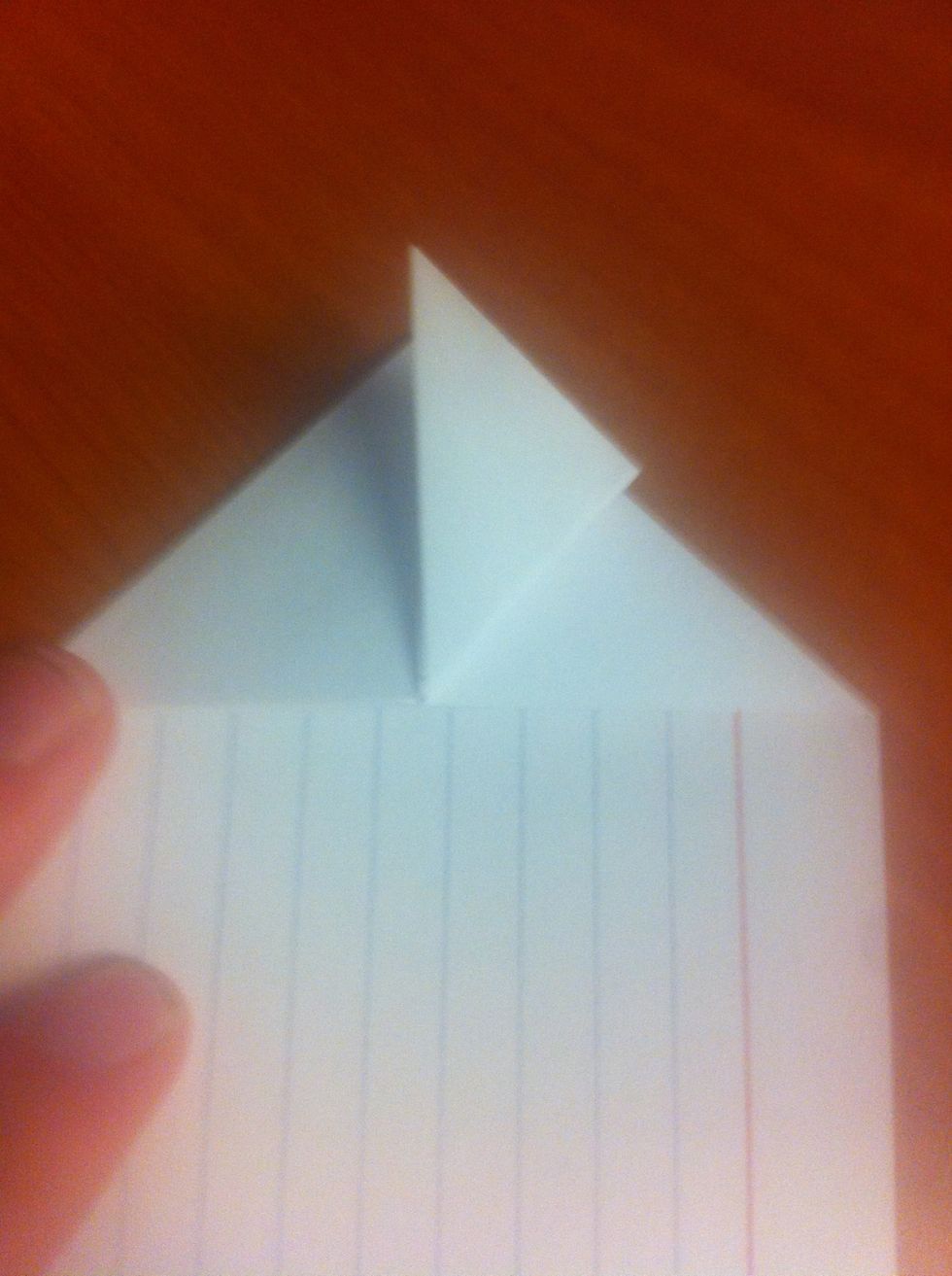 Using only the top-most layer, take the bottom right corner of the triangle and fold it to the top corner of the triangle (as shown.) repeat for the bottom left corner.