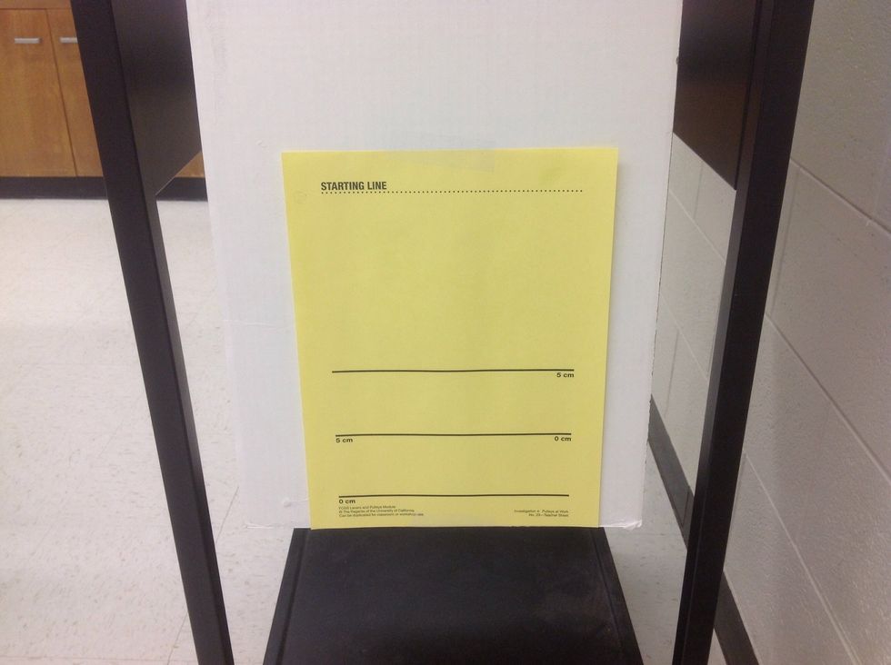 Using scotch tape, attach a yellow "starting line" sheet to the cardboard.  Line up the bottom of the sheet to the bottom of the cardboard.