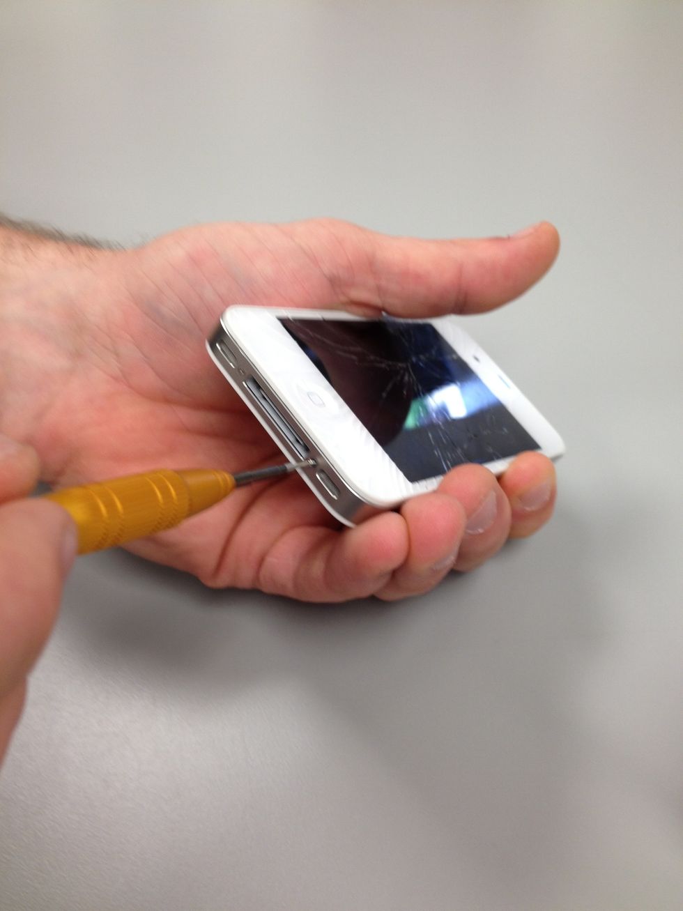 Using the appropriate screwdriver, carefully remove the two screws on the bottom near the charging port. Do you see how small these screws are? Luckily you have your ScrewMat to keep track of them.