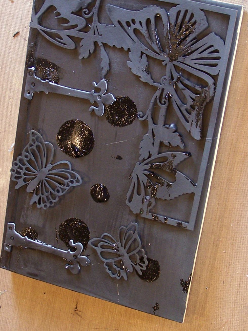 Using the Art Anthology Orbital Stencil and Black Leather Sorbet ad texture to your book cover.  allow to dry and adhere your chosen chipboard pieces to your book cover and paint with Gesso.