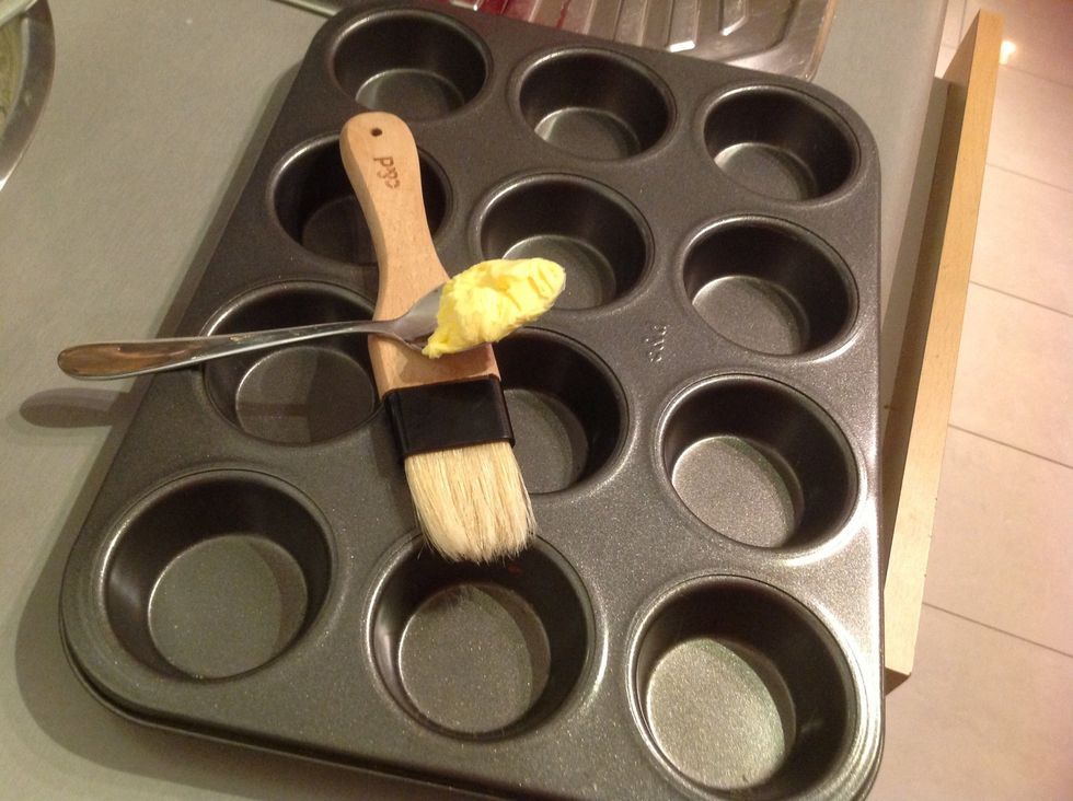 Using the brush and butter, coat the muffin tray well. This is to make sure when you take the muffins out they don't stick to the tray or break apart.