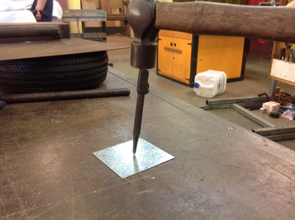 Using the centre punch and ball pein hammer, create an indent in the centre of the cross.