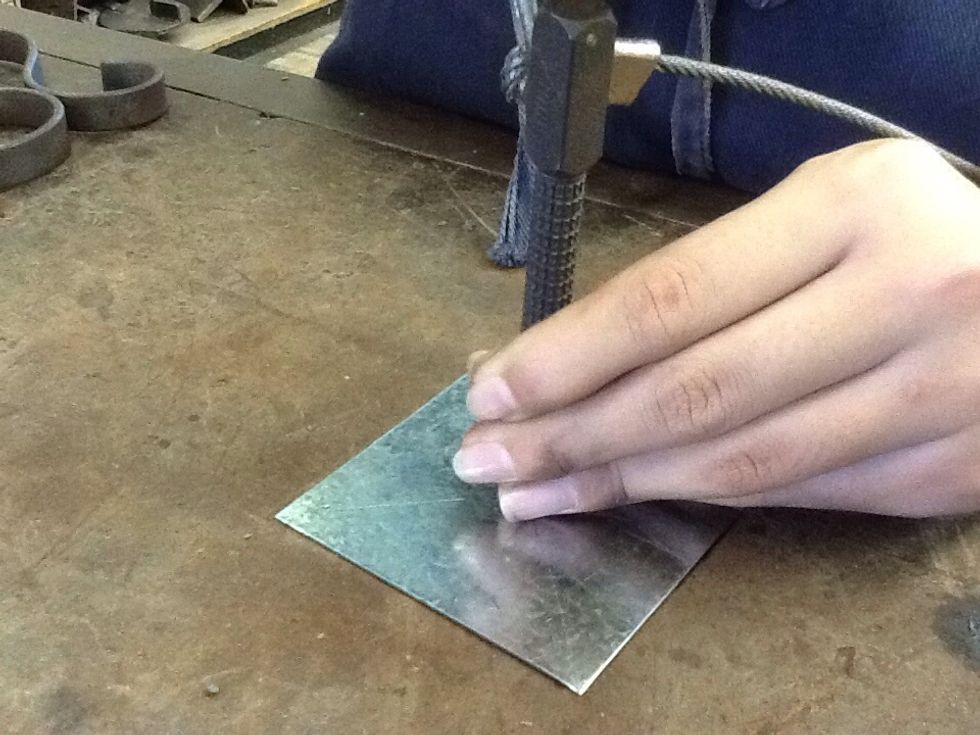 Using the centre punch and ball pein hammer, punch a hole where the middle of the cross is
