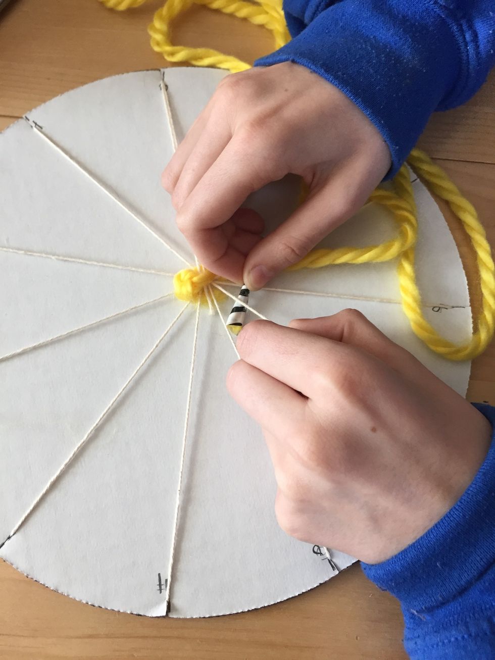 Using the "fake shoelace" taped end, begin weaving under and over the warp strings.