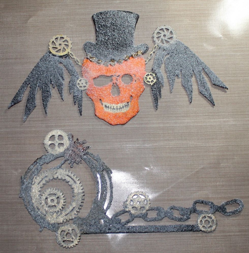 Using the Galaxy Gold stamp pad, stamp all the gears on the grunge gear and skull, once dry, paint the chipboard with Art Anthology Poppy and Tuxedo, once dry, stamp with Versamark and apply UTEE.
