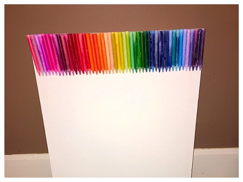 Using the hot glue gun, glue a straight line on the crayon and put into color coded groups on the canvas. Put the crayons at the top of the canvas forming a straight line.