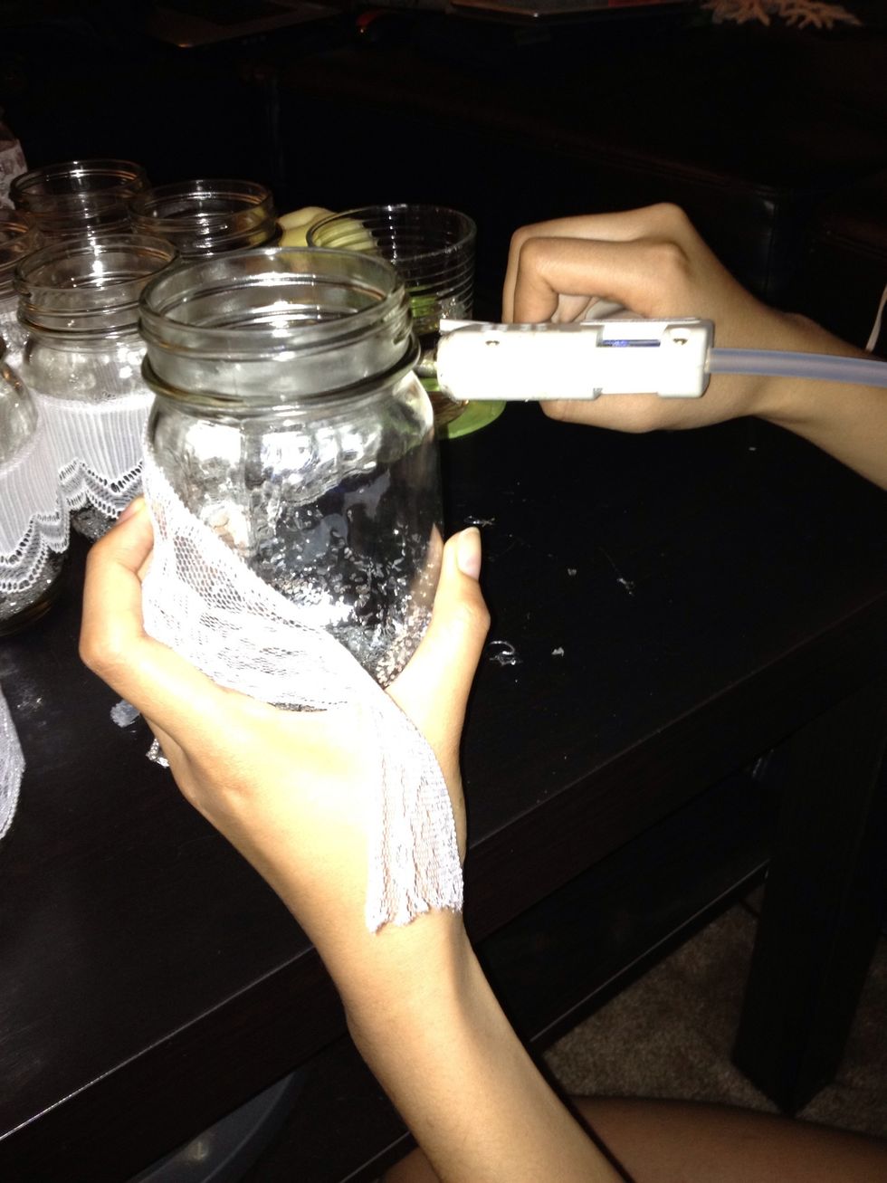 Using the hot glue gun, glue the sides of the ribbon around the jar