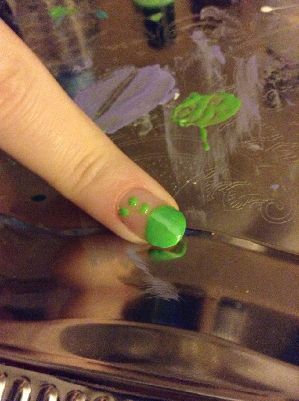 Using the larger end of the dotting tool (or toothpick), make 3 green dots above the half circle, curving the last one out to one side. This is the antennae.