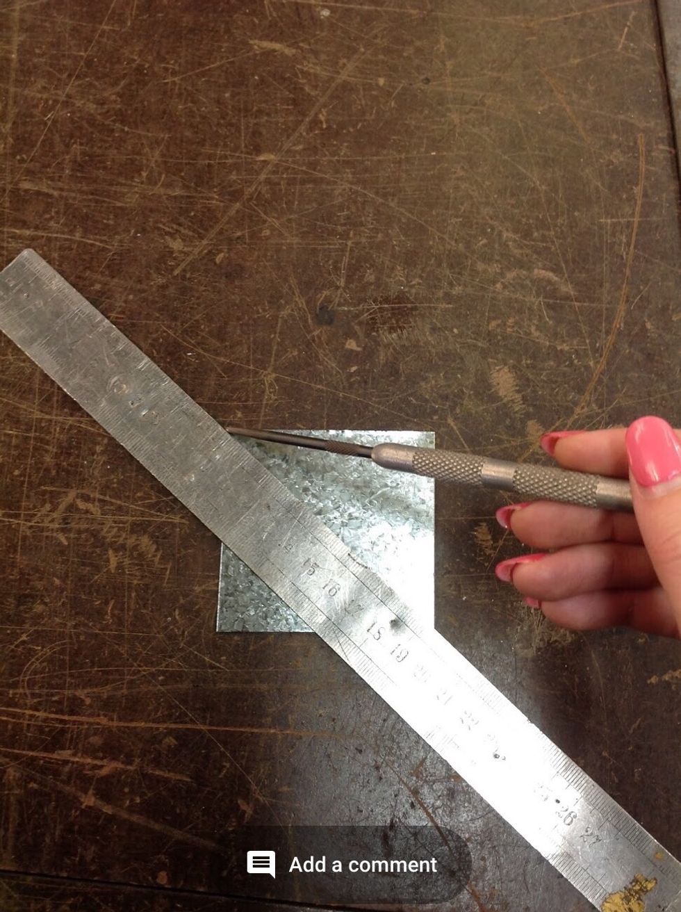 Using the metal ruler and scribe we need to find the centre, draw to straight lines from corner to corner. Leaving the middle.