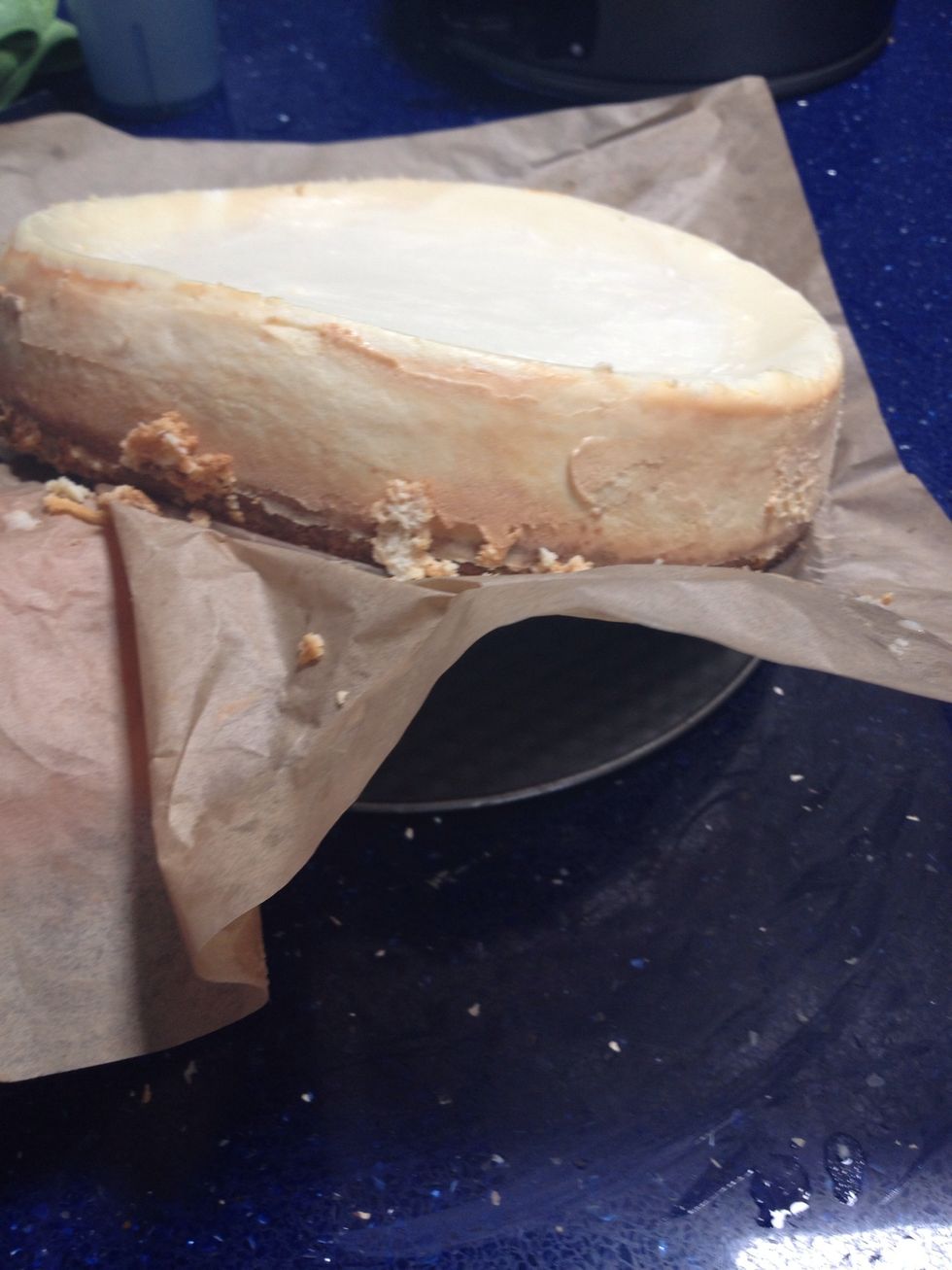 Using the piece of parchment paper, gently pull the cake off the bottom of the pan.