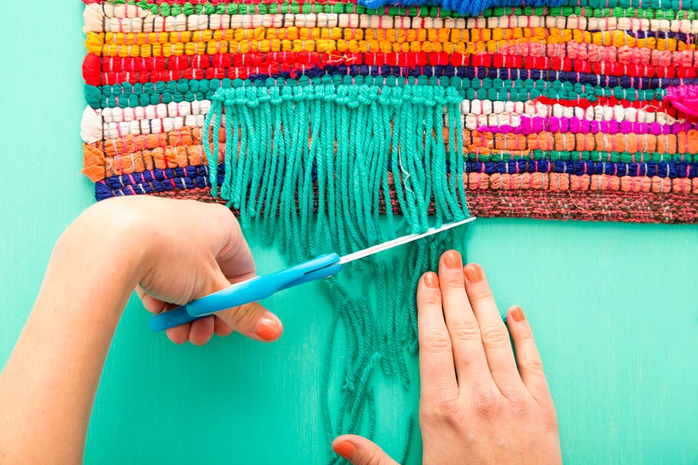 Using the same color yarn, repeat this many more times in a row, then trim the yarn. Make more lines of yarn in different colors up to the halfway point on your rug.