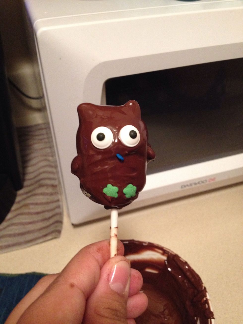 Using the same technique, dot candy coating in the position for the beak, and attach an orange rainbow chip sprinkle. Add two brown M&Ms minis for the wings.
