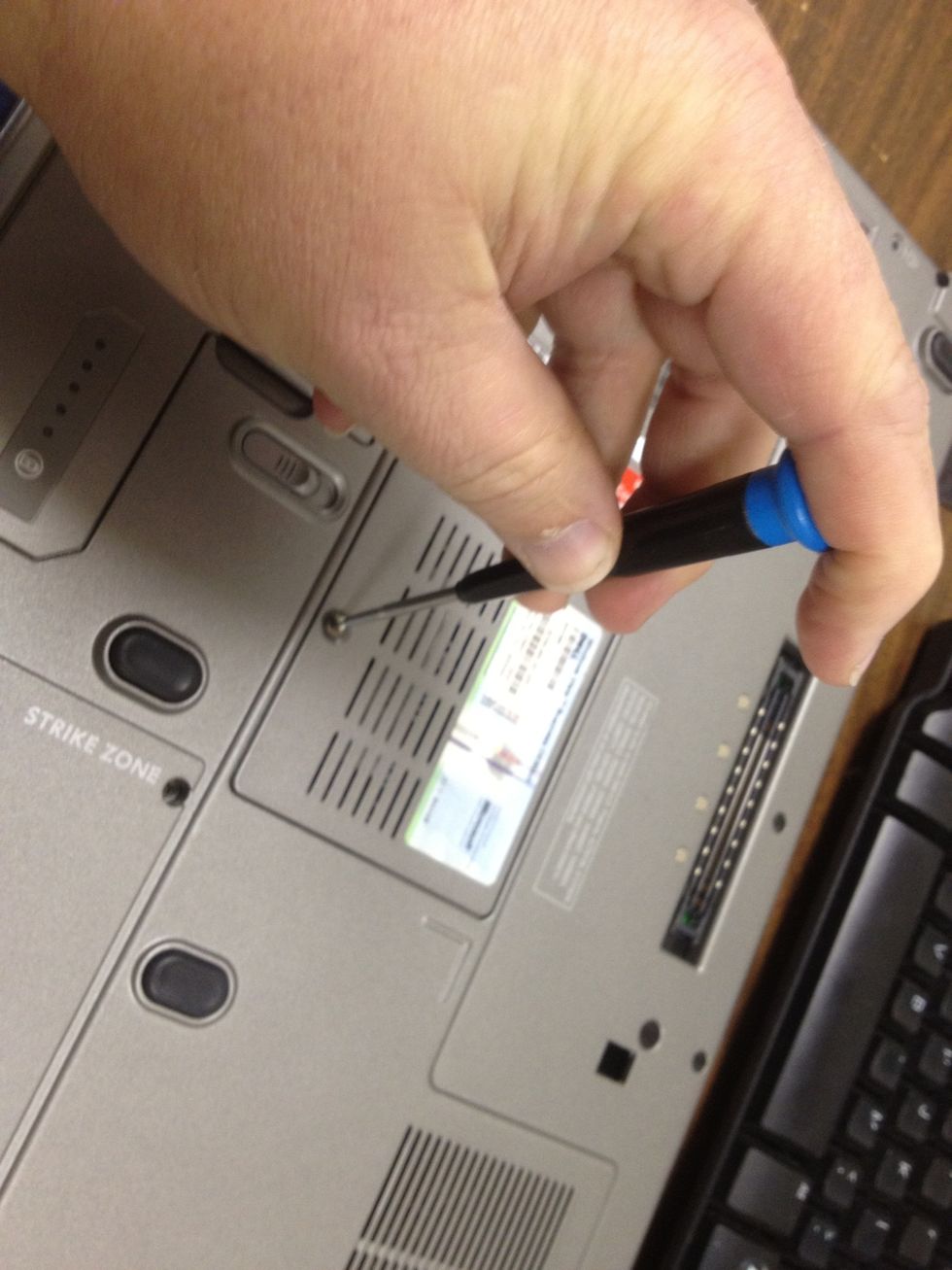 Using the small Phillips head screwdriver, loosen the screw(s) holding the memory module  cover to the laptop.