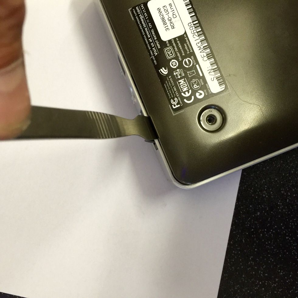 Using the spider (or plastic gift card) separate the bottom plate by inserting the spider in the small gap between the bottom case and silver band adjacent to the power button.