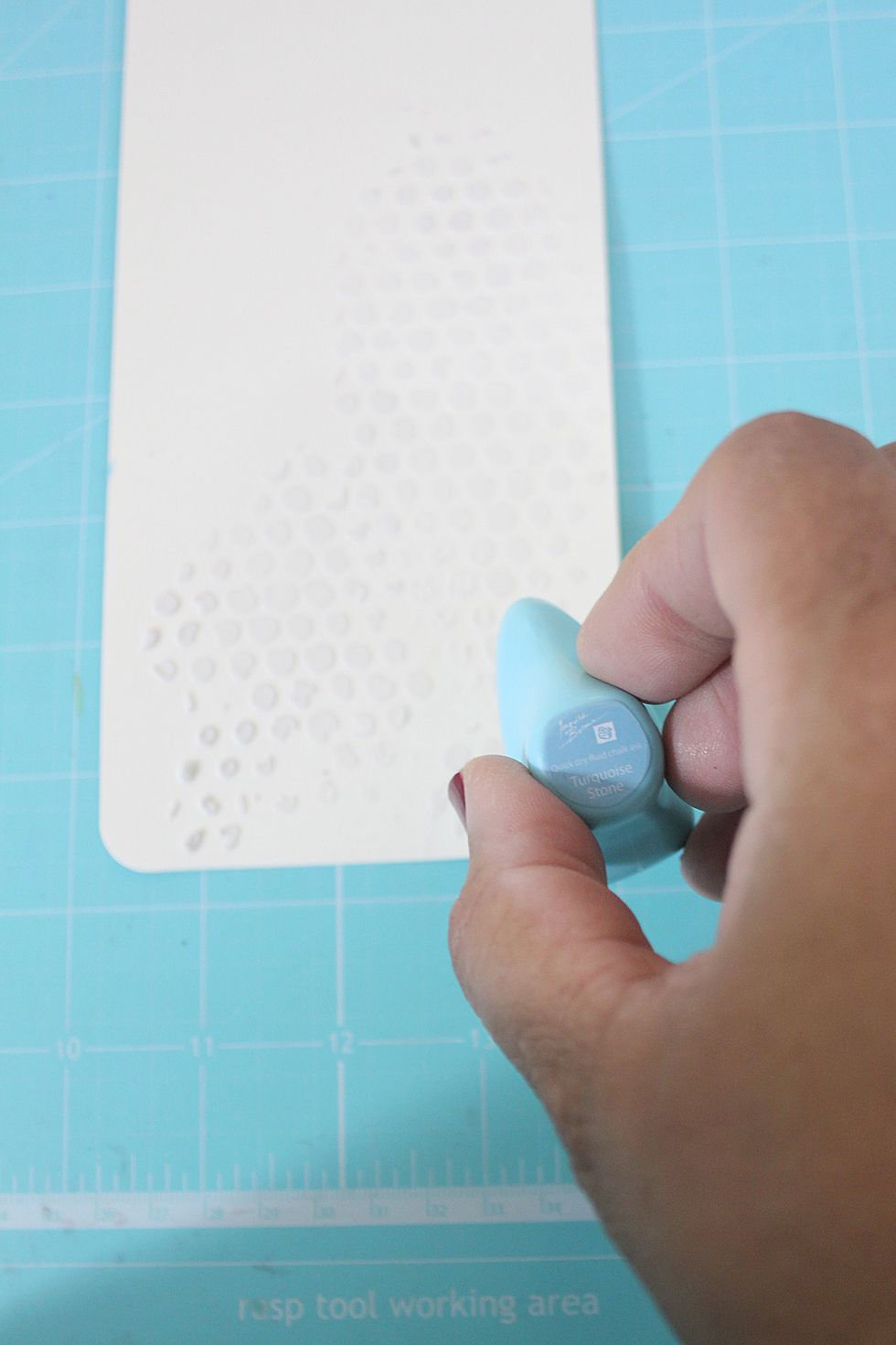Using the "Turquoise Stone" chalk inker, rub color over the stencil and to the edges of the tag.