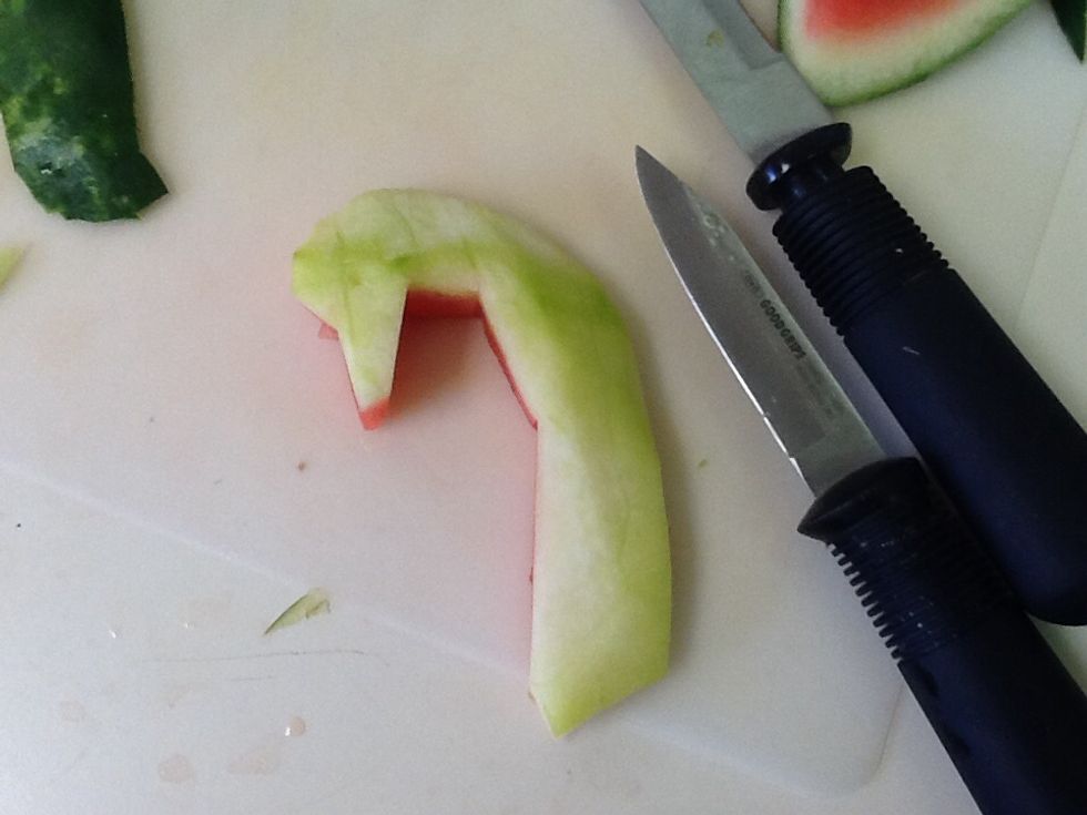 Using the utility knife, carve out the shape of the head. Then peel the skin of and smooth it out so it looks clean. Also cut of a portion of the bottom so it will be stable when inside the watermelon